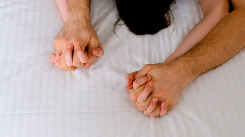 couple holding hands in bed