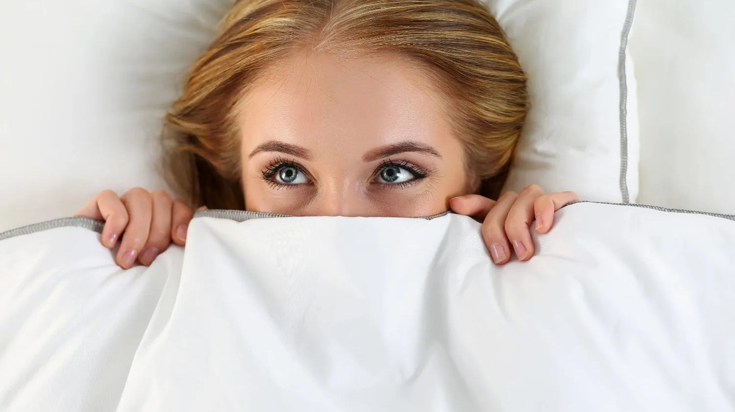 Woman hiding under bed sheets