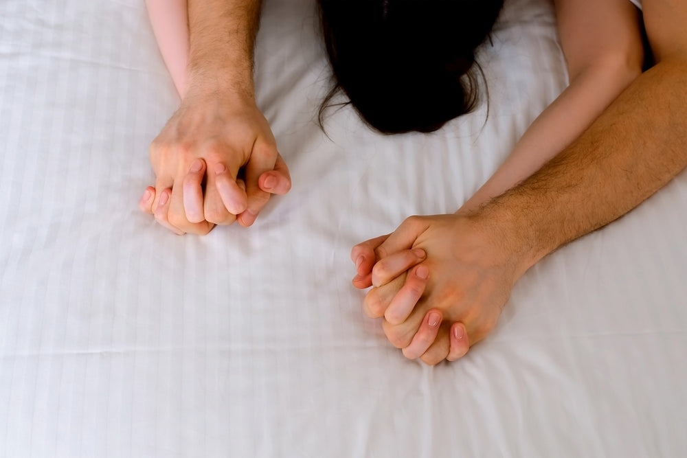 couple holding hands in bed